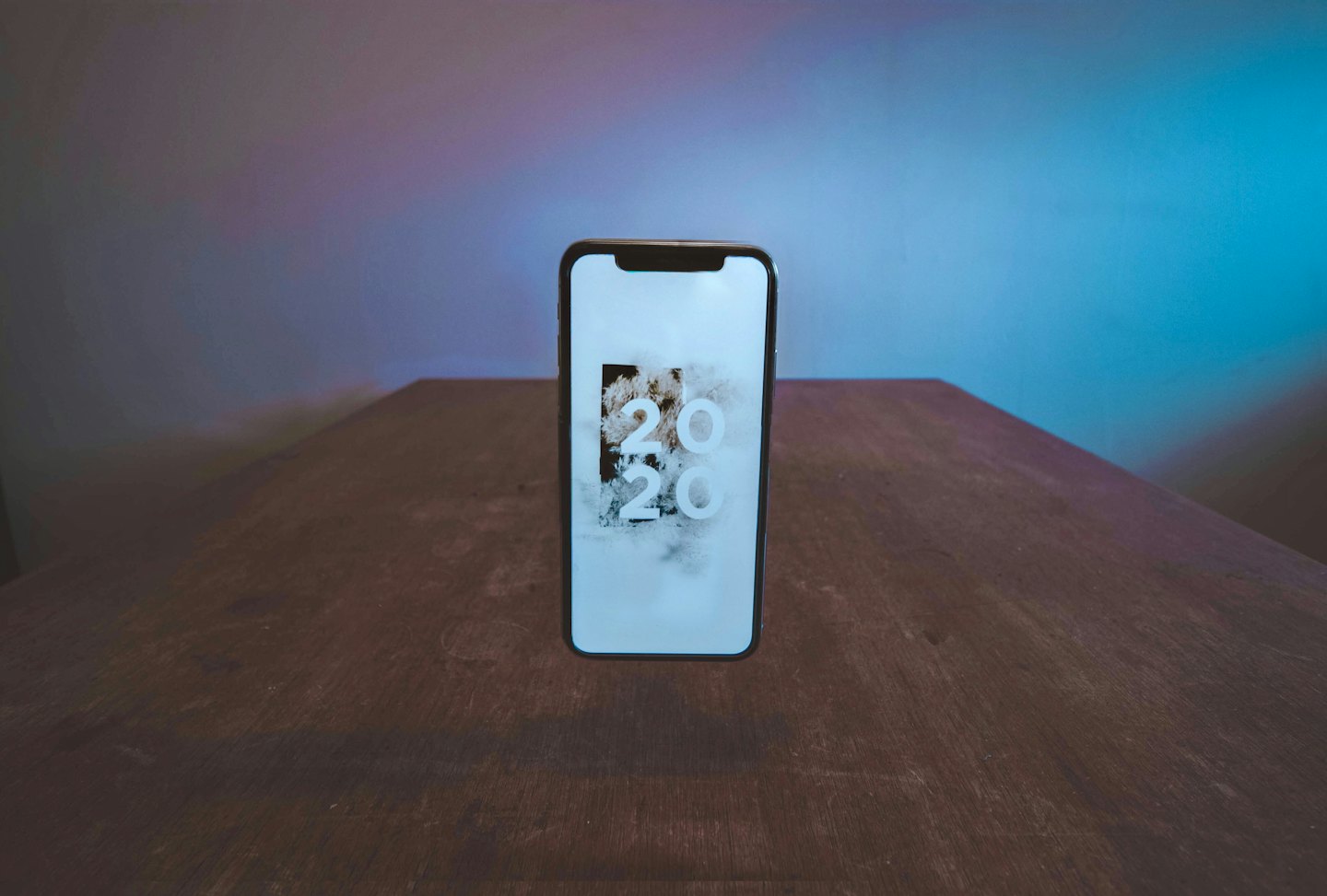 Smartphone che mostra l'anno 2020 su un tavolo di legno.