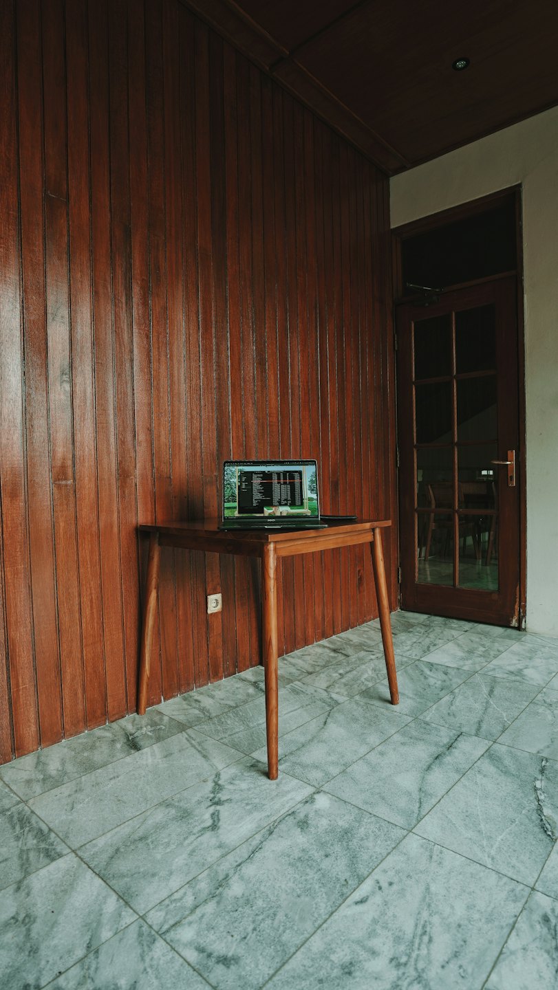 Un laptop aperto con codice visualizzato è appoggiato su un tavolo di legno.