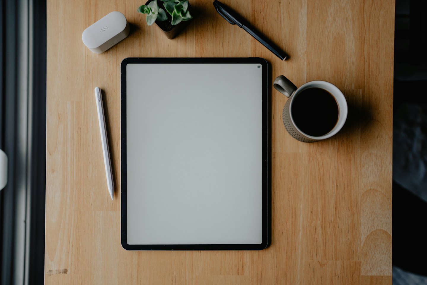 Tablet e cancelleria su una scrivania di legno.